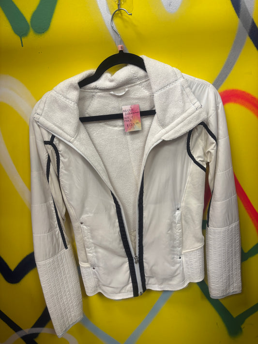 A white hooded zip-up jacket with black trim details, hanging on a black hanger against a bright yellow graffiti wall.